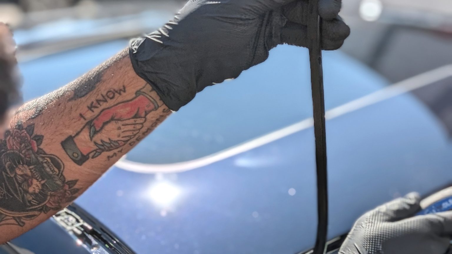 Gloved hands fitting a new windshield moulding on a car at a mobile appointment