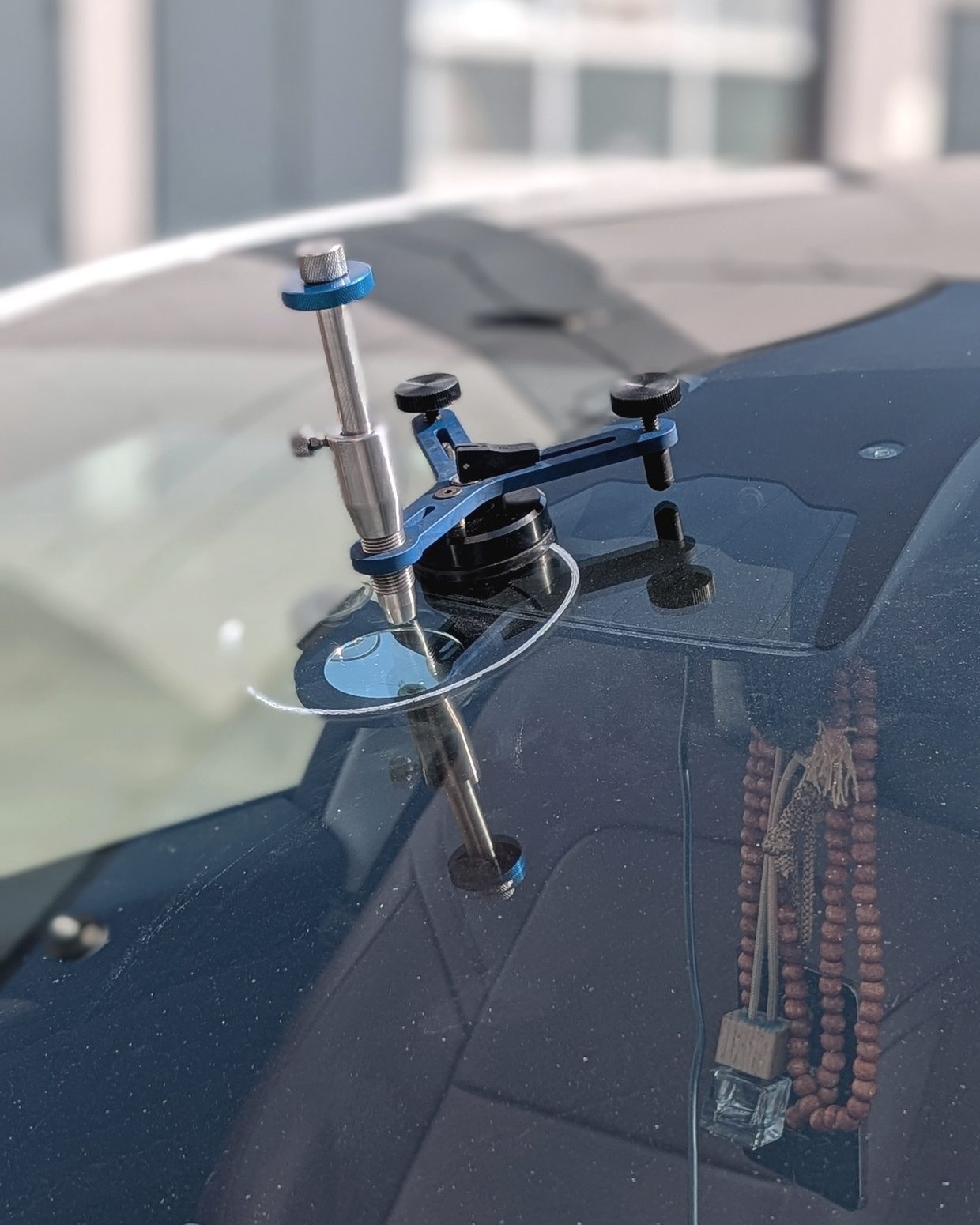 Windshield repair bridge mounted on a chipped windshield, drawing resin into the break